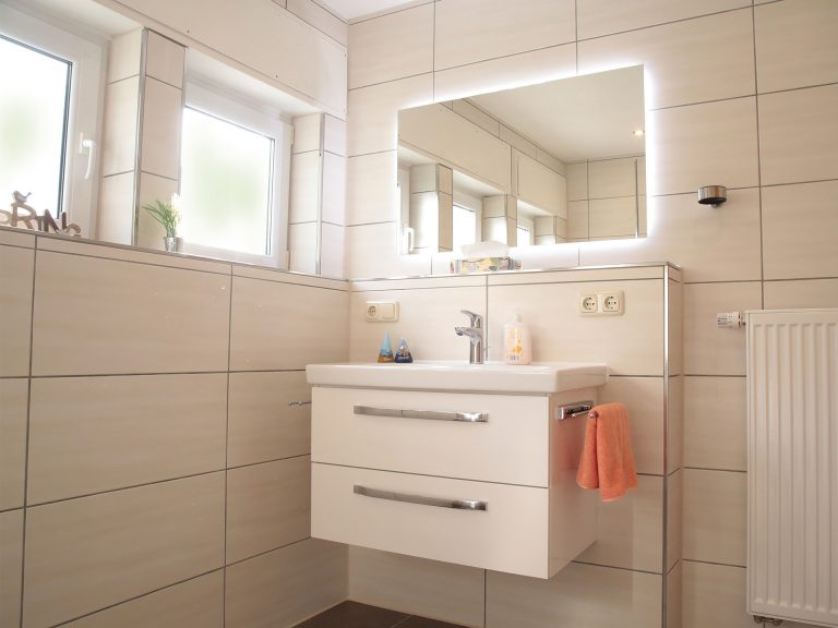 Bad der Ferienwohnung Markgraf mit Blick auf Waschbecken, Spiegel und gepflegte Einrichtung